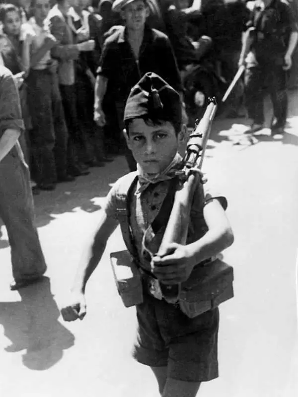 Um pequeno republicano marchando pelas ruas de um vilarejo não identificado durante a Guerra Civil Espanhola.
